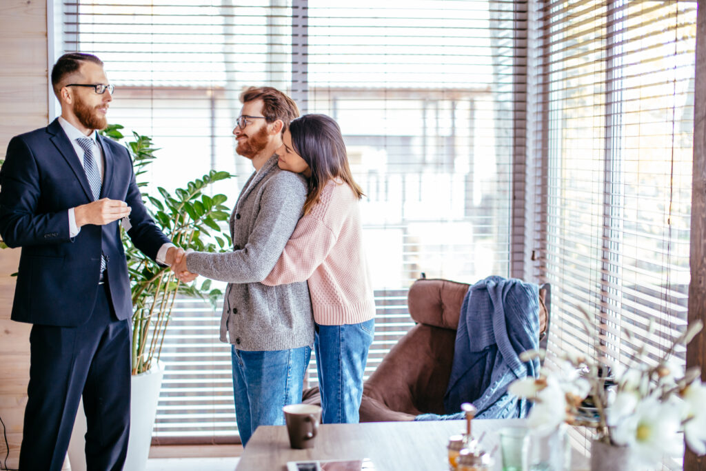 Paar schüttelt Mann in Businesskleidung die Hand