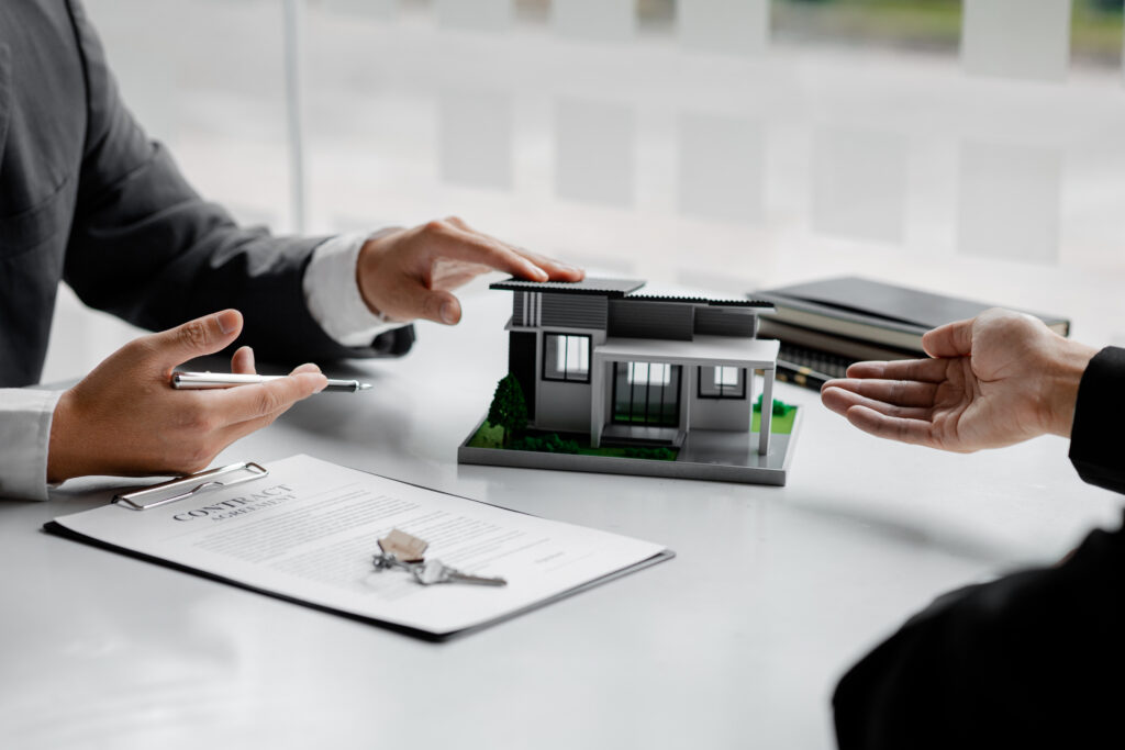 Zwei Männer mit einem Vertrag und Hausmodell