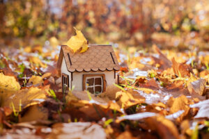 Hausmodell aus Holz im Herbstlaub